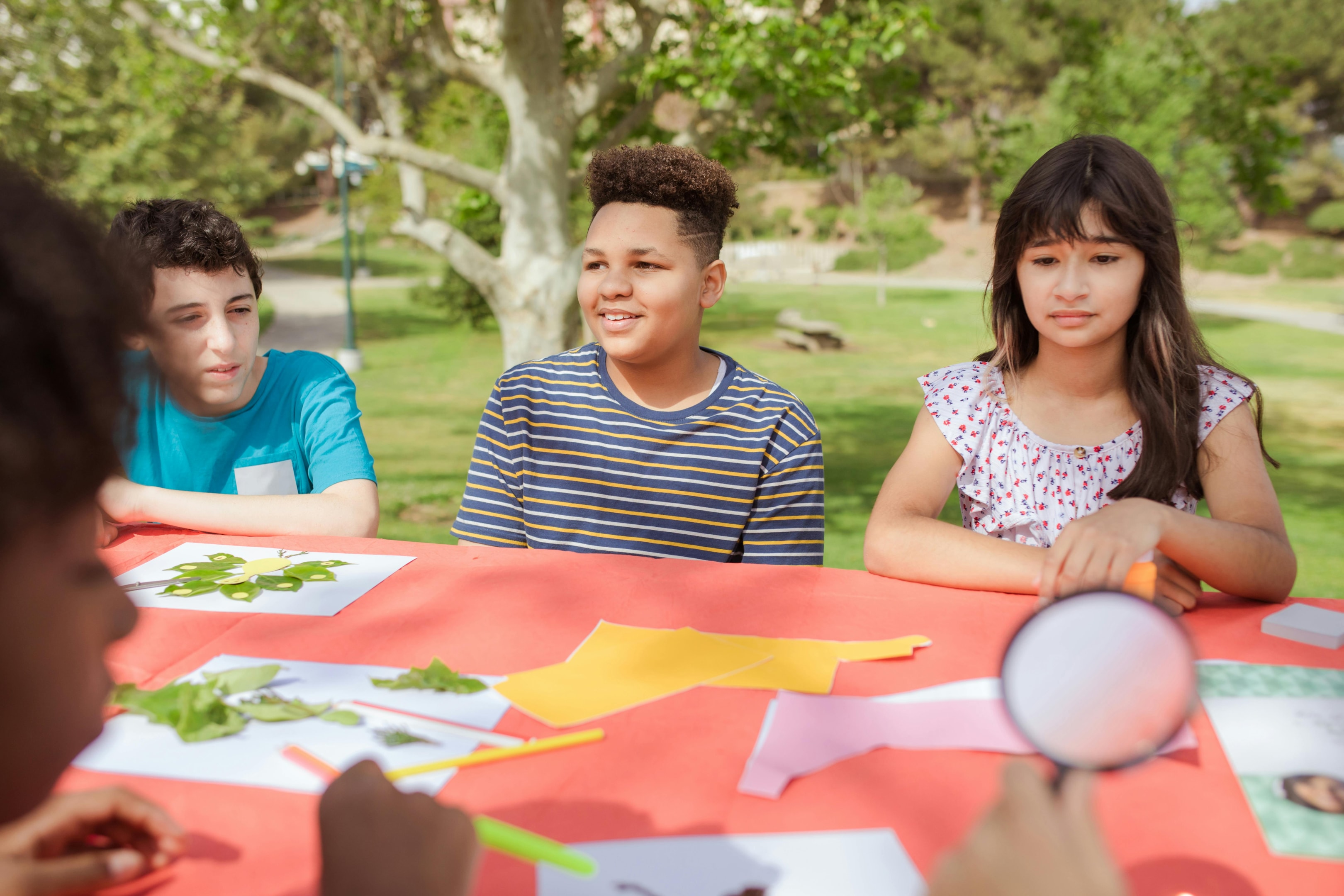 children sitting at table doing arts and crafts with autumn leaves 