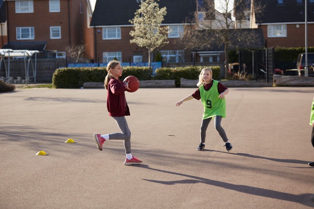 2 children playing on a court with a ball