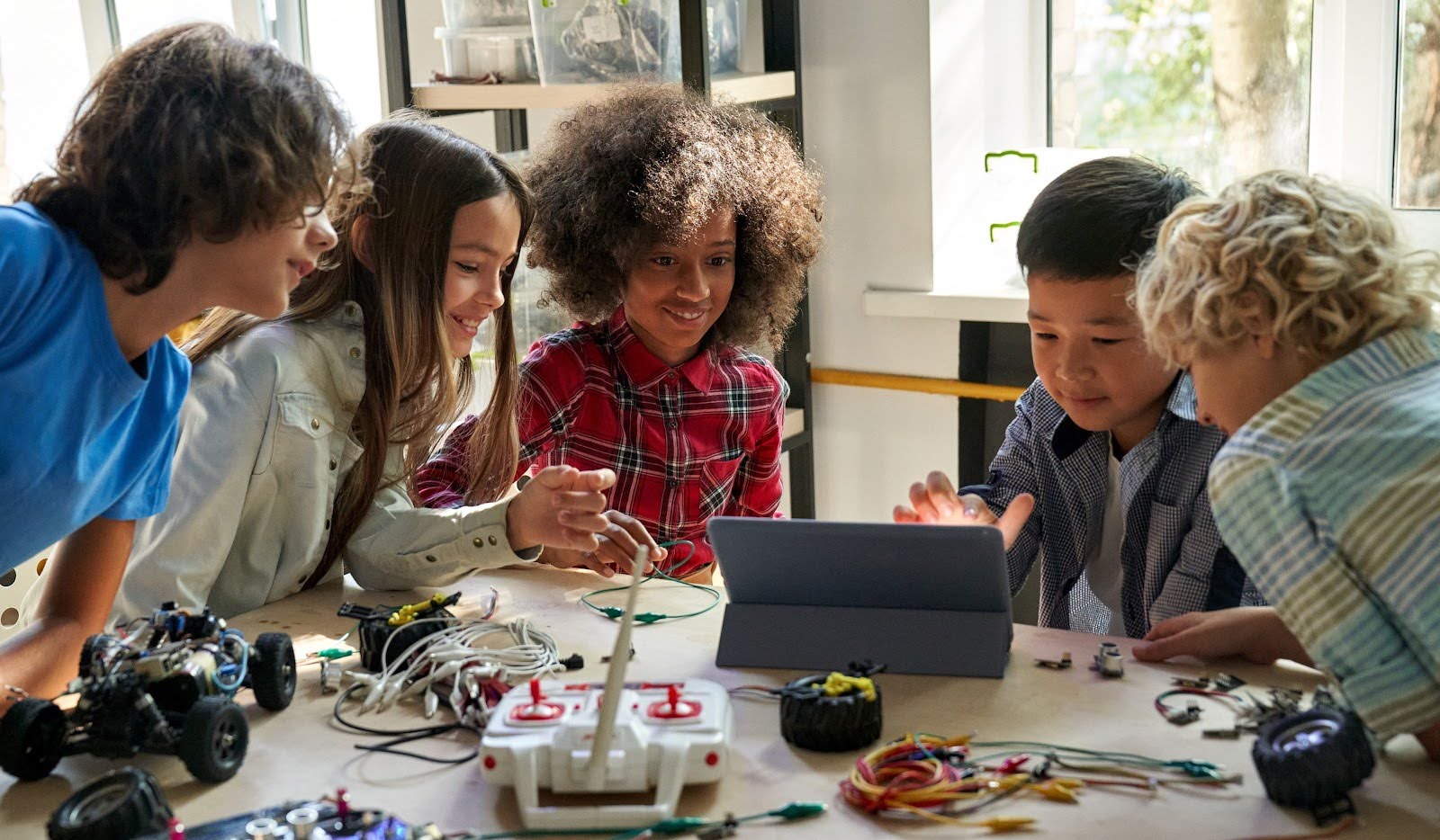 A group of children sitting around a table playing on a tablet device